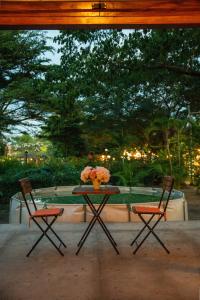 una mesa y dos sillas con un jarrón de flores. en Treellion Jungloo, en Phnom Penh