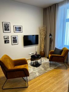 ein Wohnzimmer mit 2 Stühlen und einem Flachbild-TV in der Unterkunft Home Heart of the center of Brno - Koliště Passage in Brünn