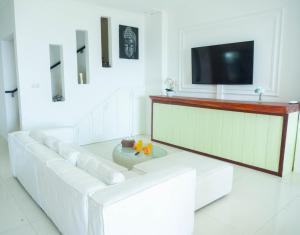 a white living room with a white couch and a tv at Sunrise Beach Villa in Sanur
