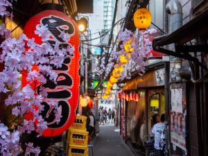 une rue de la ville avec des panneaux et des fleurs suspendus aux bâtiments dans l'établissement APA Hotel Shinjuku Kabukicho Chuo, à Tokyo