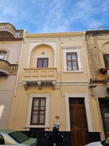 un edificio amarillo con ventanas y una puerta en Sir Patrick's rooms & hostel, en Għajn il-Kbira