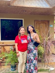 dwie kobiety stojące przed domem w obiekcie MIKI's Guest House w mieście Siquijor
