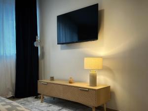 a tv on a wall with a table with a lamp at Le Cocon des Guillemins in Liège
