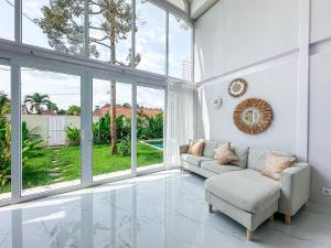 a living room with a couch and large windows at White Villa Ubud in Ubud