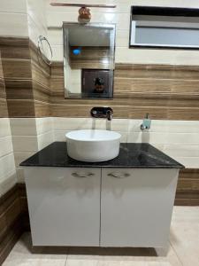 een badkamer met een witte wastafel en een spiegel bij TIC ROOMS in Siliguri