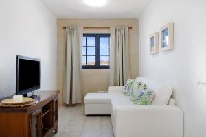 uma sala de estar com um sofá branco e uma televisão em Apartamento Cabo em Caleta de Sebo