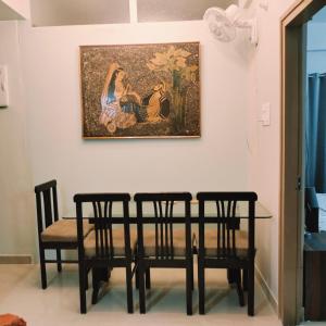 mesa de comedor con 4 sillas y un cuadro en la pared en Nester Rooms, en Guwahati