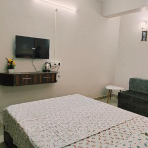 1 dormitorio con 1 cama y TV en la pared en Nester Rooms, en Guwahati