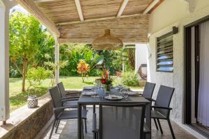 a dining table and chairs under a wooden pergola at Charming 3-Bedroom Villa with Pool in Grand Baie in Grand Baie