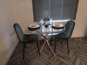 a glass table with two chairs in a room with a window at 14 Plants Yard in Worksop