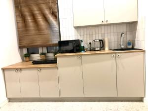 a kitchen with white cabinets and a microwave at Sands Sopot Apartments in Sopot