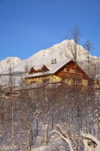una cabaña de madera en la nieve con una montaña en Privat Iva Smokovec, en Nový Smokovec