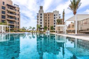 a large swimming pool with buildings in the background at Livbnb Suites - Madinat Jumeirah Living - Cozy 2 Bedroom near Burj Al Arab in Dubai
