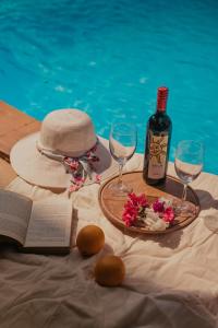 uma mesa com uma garrafa de vinho, um chapéu e copos em The Regalia Resort em Mandrem