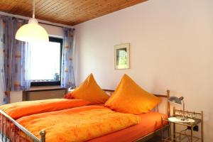 ein Schlafzimmer mit einem Bett mit orangefarbener Bettwäsche und einem Fenster in der Unterkunft Ferienwohnung Helene in Olsberg