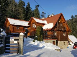 a large wooden house with snow on the ground at Dom Gościnny Dudek in Krynica Zdrój