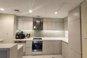 a kitchen with white cabinets and a stove top oven at DAMAC Voleo In Business Bay in Dubai