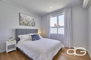 a white bedroom with a bed and a window at Federal Apartments South Fremantle in South Fremantle