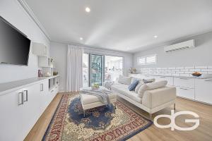 a white living room with a couch and a table at Federal Apartments South Fremantle in South Fremantle