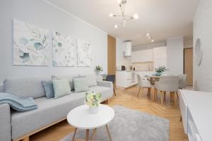 ein Wohnzimmer und eine Küche mit einem Sofa und einem Tisch in der Unterkunft Zajezdnia Wrzeszcz Modern & Stylish Apartment Gym Gdańsk by Renters in Danzig