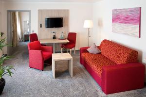a living room with two red chairs and a table at Haus Anna an der Stadtmauer in Hanau am Main