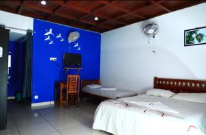 una camera con due letti e una parete blu di Mundro Garden Homestay a Munroe Island