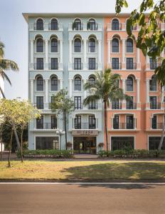 a large building with palm trees in front of it at Su Casa Phu Quoc Long Beach in Phú Quốc