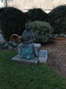 Eine Statue einer Frau, die auf einer Bank sitzt. in der Unterkunft Appartement privé in Lourdes