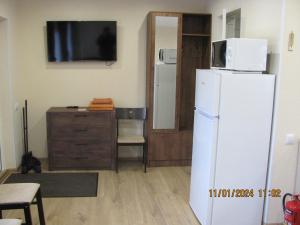 a kitchen with a white refrigerator and a tv at ziedu pasaule 2 in Krāslava