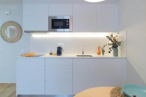 a white kitchen with a sink and a microwave at Budget Beach Studio 23 in Sant Antoni de Calonge +8 photos