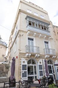 a building with tables and umbrellas in front of it at Concetta Studio Apartments in Cospicua