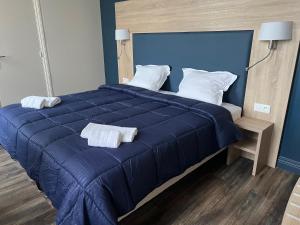 a blue bed with two white towels on it at Armor Hotel in Compiègne