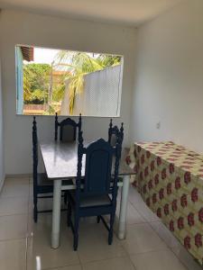 een tafel en stoelen in een kamer met een raam bij Casa na praia d’Ulé in Guarapari