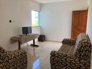 een woonkamer met 2 stoelen en een tafel met een tv bij Casa na praia d’Ulé in Guarapari