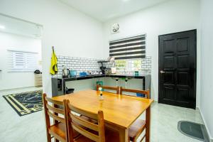 - une cuisine avec une table et des chaises en bois dans l'établissement De Sungai Langkawi Guesthouse, à Pantai Cenang