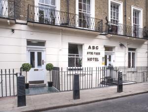 a white building with two windows and a fence at ABC Hyde Park Hotel in London