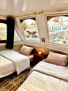 two beds in a room with two windows at Houseboat Hotel and Nile Cruises Zainoba in Nag` el-Ramla