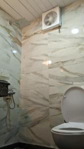 a bathroom with a toilet and a stone wall at Royal Crown Hotel عائلات فقط in Alexandria