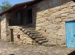Amoeiro的住宿－Habitaciones con baño individual en Casa de campo. Piscina.，一座石头建筑,设有蓝色的门和一些楼梯
