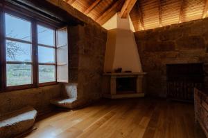 uma sala de estar com lareira e uma grande janela em Habitaciones con baño individual en Casa de campo. Piscina. em Amoeiro