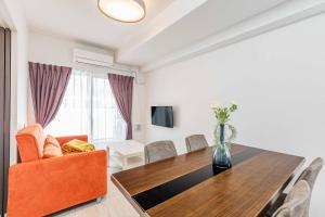 a living room with a dining room table and orange chair at FDS Plaisir in Osaka