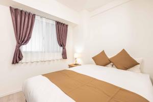 a white bedroom with a bed and a window at FDS Plaisir in Osaka