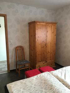 a bedroom with a wooden cabinet and a chair at Ferienwohnung Nordmoor in Blomberg