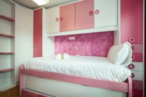 Dormitorio femenino con paredes rosas y blancas y litera en Casa Nerai Apartamento, en Gijón