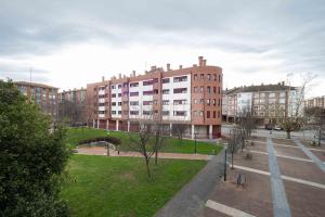 un gran edificio de ladrillo con un parque delante de él en Casa Nerai Apartamento, en Gijón