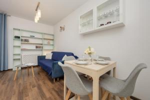 a living room with a table and a blue couch at Trzy Żagle - City View Apartments with Balcony by Renters in Gdańsk