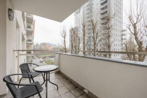 a balcony with two chairs and a table and a window at Trzy Żagle - City View Apartments with Balcony by Renters in Gdańsk