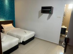 Habitación pequeña con 2 camas y baño. en Codidik Hotel, en Kuantan