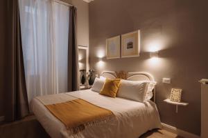 een slaapkamer met een bed met witte lakens en gele kussens bij Rooms Genova dei Rolli in Genua