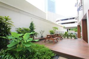 une terrasse en bois avec bancs et plantes sur un bâtiment dans l'établissement Greatwood Residence at Devonshire, à Singapour